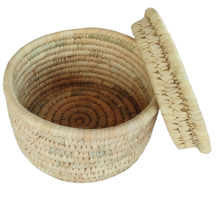 Pyöreä palmulehdistä punottu kori, halkaisija 28 cm, sivulle kallistuva kansi ja näkyvä sisätila.